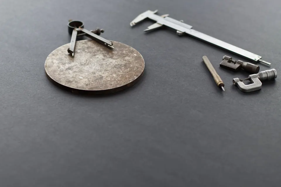 Instruments de mesure de précision sur une surface gris foncé : pied à coulisse, compas, micromètre et disque de métal